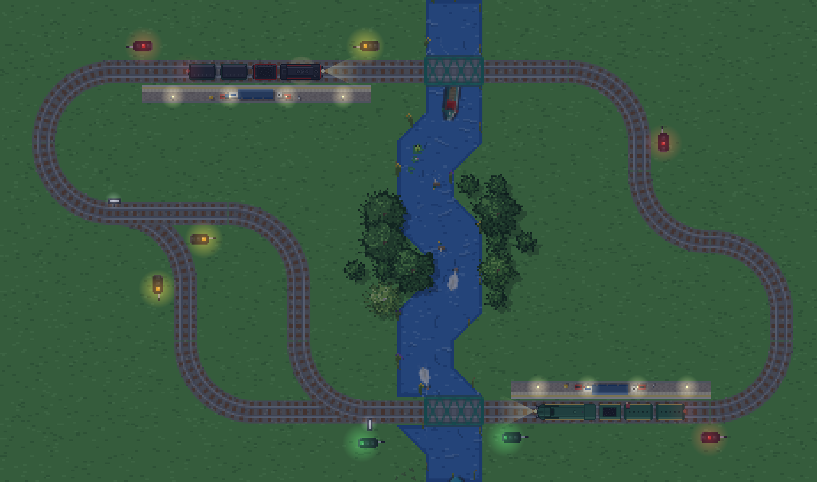 The same circuit at dusk: the grass has gone dark, signal lamps and platform lights glow, and the trains' headlights throw beams down the track.